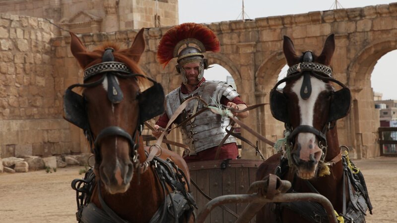 Josh Gates steuert als römischer Zenturio verkleidet einen Streitwagen in Amman, Jordanien. – Bild: Warner Bros. Discovery