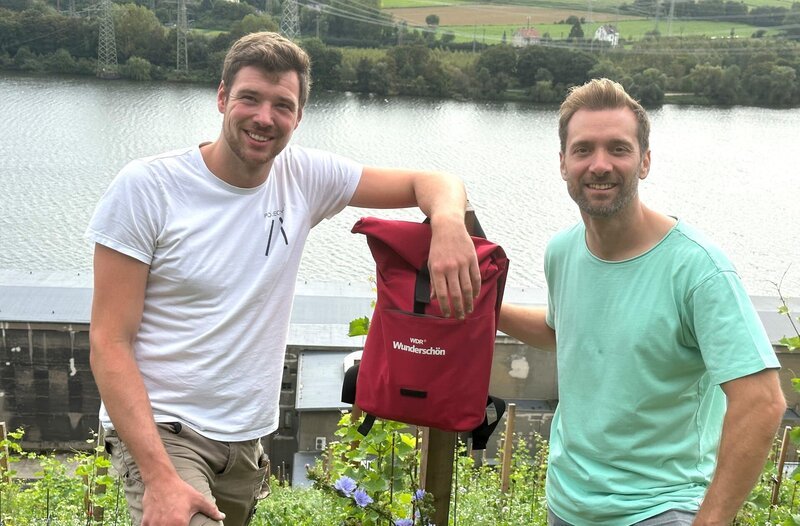 Moderator Daniel Aßmann (r) mit Elias Sturm, der hat einen Weinberg am Koepchenwerk angelegt hat. – Bild: WDR/​Michael Wieseler