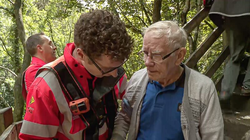 James hört einem älteren Patienten zu, während Tyrone im Hintergrund zu sehen ist. – Bild: Discovery Communications