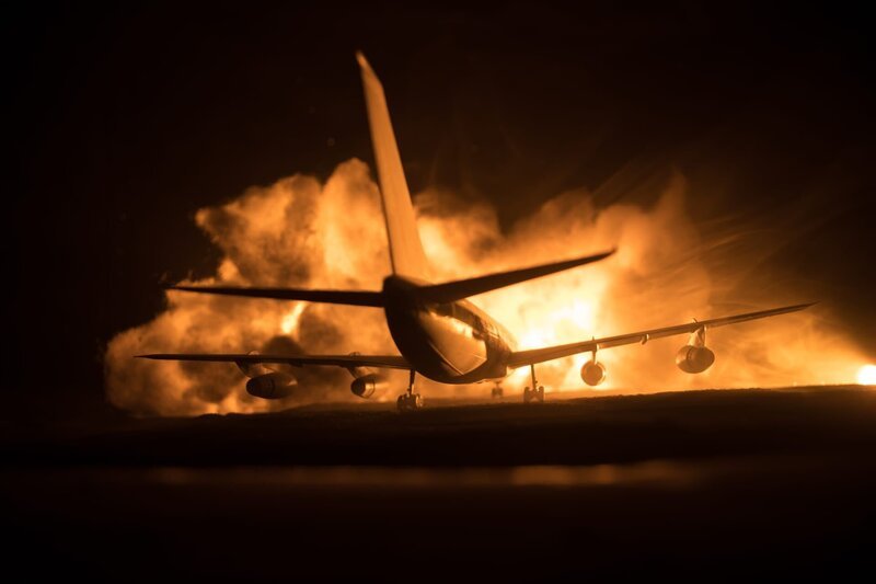 Air Crash. Burning falling plane. The plane crashed to the ground. Decorated with toy at dark fire background. Air accident concept. Selective focus. – Bild: zeferli@gmail.com/​depositphotos