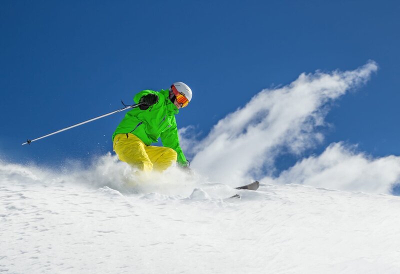 Skifahrer beim Abfahrtslauf im Hochgebirge an einem sonnigen Tag. – Bild: Depositphotos /​ Lukas Gojda /​ Kesu01