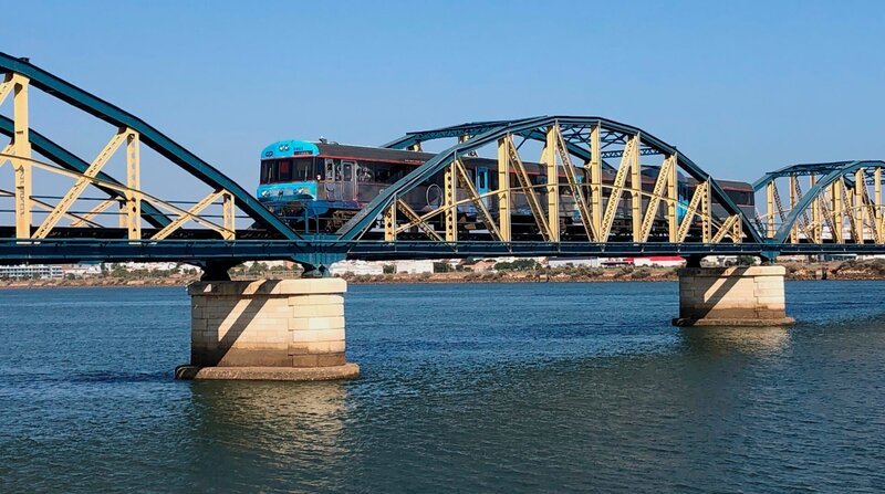 Der Zug überquert den Fluss Arade bei Portimão. Der Bau der Eisenbahn-Brücke war ein wichtiger Meilenstein für die Menschen in der westlichen Algarve. Fischkonserven und landwirtschaftliche Produkte konnten so leichter abtransportiert werden. – Bild: SWR/​Kirsten Ruppel /​ ZDF