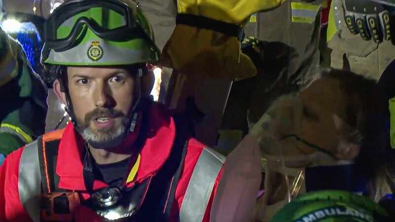 Dr. Steve Rowe inmitten der Feuerwehrleute und Sanitäter, rechts der Patient mit Sauerstoffmaske. – Bild: Discovery Communications