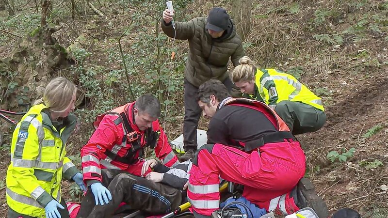 Matt Syratt und Darren James mit zwei NHS-Sanitätern und einem Freund, die einem Patienten auf eine Schaufeltrage helfen. – Bild: Really /​ Air TV;Ep2 – 5.png /​ Discovery Communications