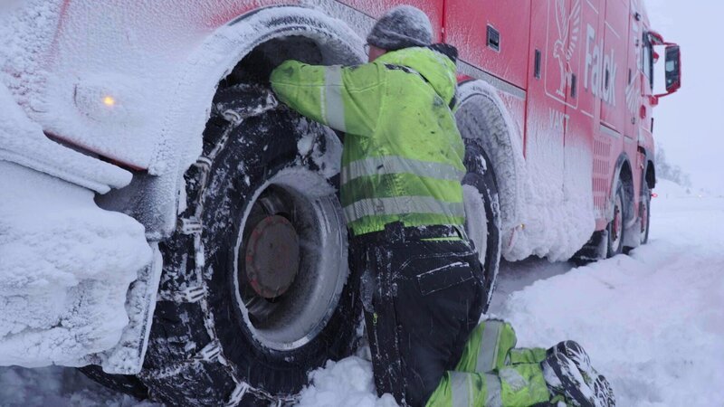 Jan Erik „The Hammer“ attaches chains to the rescue truck. They’re about to pull an empty truck up a hill and need extra traction in Hardangervidda, Norway. – Bild: National Geographic