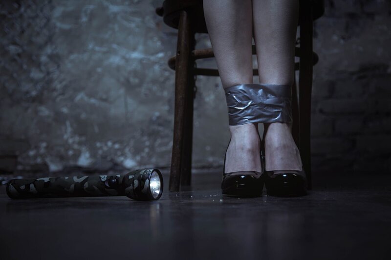 Chained up. Protectless scared tender lady sitting on a chair while her ankles being tied up and a flashlight lying beside her – Bild: Depositphotos, Inc. USA