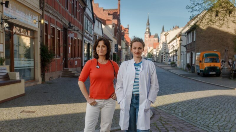 Die Spurensuche nach ihrer leiblichen Mutter führt Dr. Holly Sass (Karoline Teska, r.) in die Praxis von Dr. Katrin Herz (Inka Friedrich, l.). Da diese gerade eine Vertretung sucht, findet sich Holly unversehens als Landärztin wieder. – Bild: Stefan Erhard