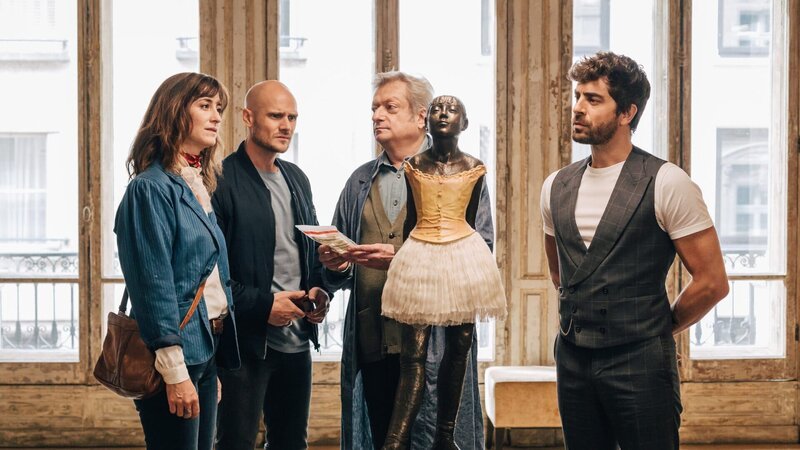 Arsčne Gosselin bestätigt Florence Chassagne und Antoine Verlay, dass es sich bei der Mordwaffe um das Haarband der Statue „Scary Mary“ handelt, woraufhin diese den Schuldirektor Esteban Cortes nach mehr Informationen über die Statue fragen. – Bild: Caroline Dubois/​FTV