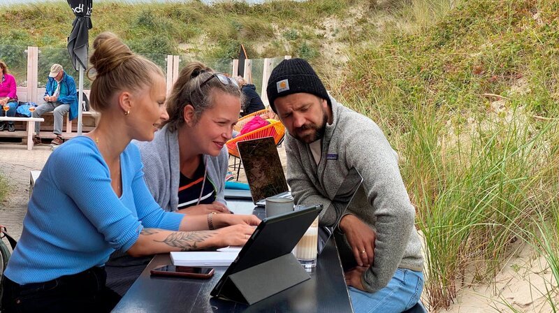 Ben Hinrichs ist ganz neu auf der Insel Baltrum, aber er möchte die Politik der Insel gleich mitgestalten. Er kandidiert für „Moin Baltrum“. Seine Frau Merle (links) und Redakteurin Constanze Gaiser (rechts) beraten den zugezogenen Insulaner. – Bild: Katrin Heineking Ben Hinrichs ist ganz neu auf der Insel Baltrum, aber er möchte die Politik der Insel gleich mitgestalten. Er kandidiert für „Moin Baltrum“. Seine Frau Merle (links) und Redakteurin Constanze Gaiser (rechts) beraten den zugezogenen Insulaner. – Bild: Katrin Heineking