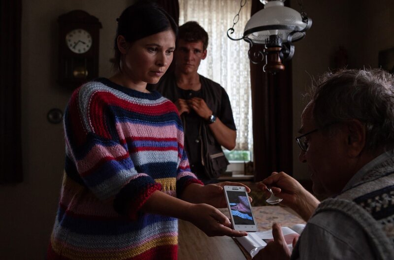 Lisa (Anna Fischer) zeigt ihrem Vater Alfons (Hartmut Volle) und Hannes (Frederik Bott) Fotos von den Würgemalen an der Leiche. – Bild: ARD Degeto/​SWR/​Daniel Schmid