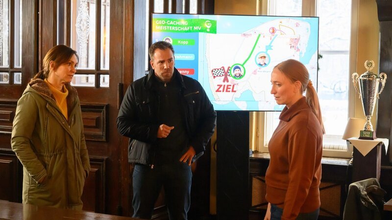 Geocaching? Karoline Joost und Lars Pöhlmann hören zum ersten Mal davon. Die Leiterin des Spiels, Anne Patzinger, erläutert es ihnen. Für den Mord hat sie allerdings keine Erklärung. – Bild: ZDF/​Meyerbröker