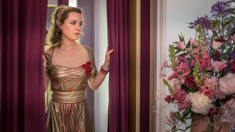 Mia Goldig (Klara Deutschmann) erstrahlt in ihrem neuen Kleid, um auf dem Empfang des Botanischen Gartens Sponsoren gewinnen zu können. – Bild: Boris Laewen