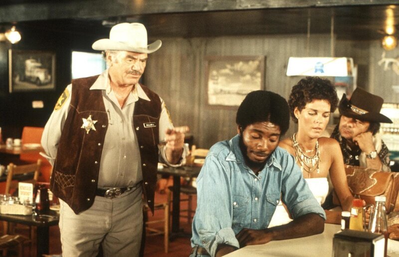 Der unsympathische und gemeine Sheriff Wallace (Ernest Borgnine, l.) schikaniert ‚Spider Mike‘ (Franklin Alaye, 2.v.l.), Melissa (Ali MacGraw, 2.v.r.) und ‚Pig Pen‘ (Burt Young, r.) bis aufs Blut … – Bild: Servus TV Der unsympathische und gemeine Sheriff Wallace (Ernest Borgnine, l.) schikaniert ‚Spider Mike‘ (Franklin Alaye, 2.v.l.), Melissa (Ali MacGraw, 2.v.r.) und ‚Pig Pen‘ (Burt Young, r.) bis aufs Blut … – Bild: Servus TV
