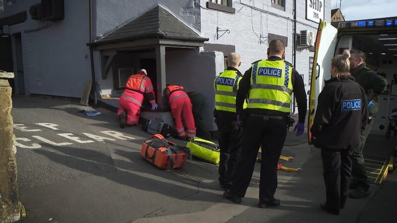 Rettungssanitäter helfen einem Mann am Unfallort. – Bild: Warner Bros. Discovery