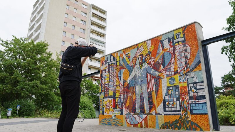 Martin Maleschka fotografiert das Kunstwerk ÑWeltall, Erde, Menschì vor Plattenbauten in Eisenh¸ttenstadt. – Bild: Axel Schneppat /​ ZDF
