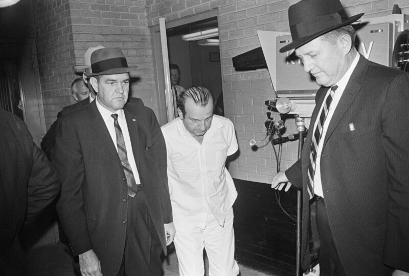 Polizeibeamte eskortieren Jack Ruby, den Mörder des mutmaßlichen Präsidentenmörders Lee Harvey Oswald, aus dem Stadtgefängnis von Dallas in eine Bezirkseinrichtung in Texas. Während einer solchen Verlegung erschoss Ruby Oswald. (Bettmann Archive/​Getty Images) – Bild: Bettmann Archive/​Getty Images