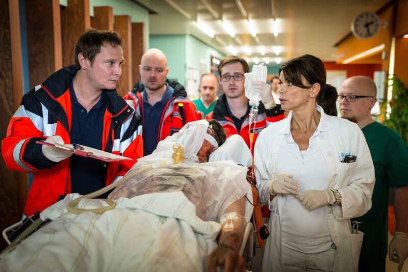 Dr. Haase (Fabian Harloff, l.) übergibt Dr. Jonas (Gerit Kling, r.) den Sprayer Lukas (Komparse), der beim nächtlichen Sprayen im Betriebswerk der U-Bahn von einem Stromschlag lebensbedrohlich verletzt wurde. – Bild: Boris Laewen