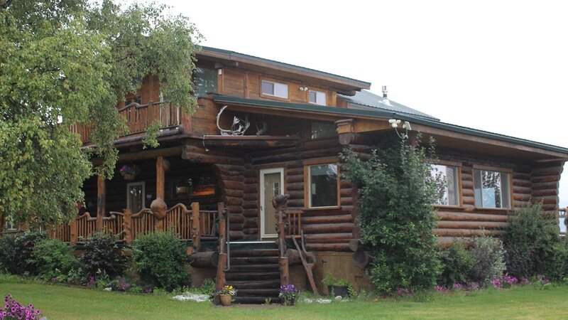 Exterior, cabin style house with many wood burls as d?cor, shot of front door with antlers on the roof, one of the stops in the Bushatz house search, at Scott Road House, Fairbanks, Alaska, as seen on Great American Country’s Living Alaska – Bild: Great American Country/​Scripps Networks, LLC