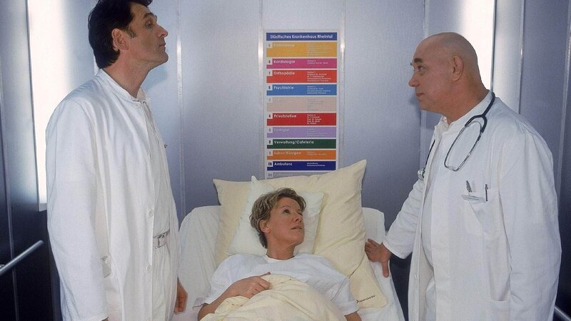 Nikola (Mariele Millowitsch, lieg.) hat sich dafür entschieden, dass Dr. Hildebrandt (Hans Martin Stier, r.) ihre Operation durchführen soll. Dr. Schmidt (Walter Sittler) ist deswegen völlig vor den Kopf gestoßen … – Bild: MG RTL D