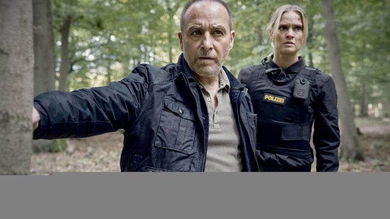 Semir (Erdogan Atalay) und Vicky (Pia Stutzenstein) verfolgen den Geiselgangster und finden eine Blutspur im Wald. – Bild: RTL /​ Guido Engels