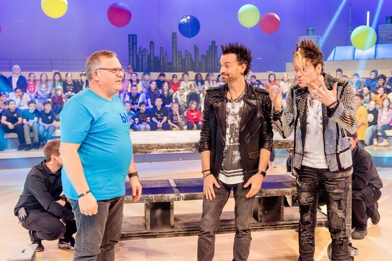 Elton (l.) versucht die Illusion der Ehrlich Brothers Chris (r.) und Andreas (M.) zu entschlüsseln. – Bild: ZDF/​Nadine Rupp