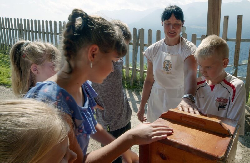 Luzia Kupplewieser lehrt die Kinder bei der Verarbeitung von Butter. – Bild: GEOSFILM