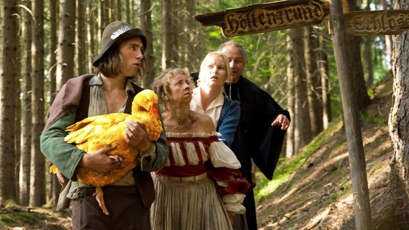 Noch ist der Weg zum Schloss weit für den Dummling (Jeremy Mockridge), die Goldene Gans, die Wirtstöchter Liesel (Anna Böttcher) und Lotte (Teresa Weißbach) und den Pfarrer (Hilmar Eichhorn). – Bild: Katharina Simmet Noch ist der Weg zum Schloss weit für den Dummling (Jeremy Mockridge), die Goldene Gans, die Wirtstöchter Liesel (Anna Böttcher) und Lotte (Teresa Weißbach) und den Pfarrer (Hilmar Eichhorn). – Bild: Katharina Simmet