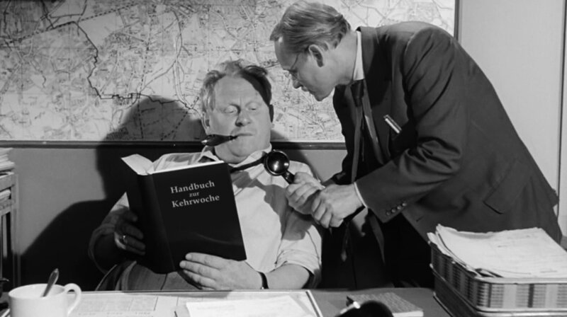 Der schwäbische Komiker Dodokay, Dominik Kuhn, nimmt sich Fritz Langs Klassiker „Die 1000 Augen des Dr. Mabuse“ an und drückt diesem Werk seinen ganz eigenen Stempel auf. Kommissar Jürgen Krass (Gert Fröbe) erhält einen brisanten Anruf durch Kriminalassistent Keyer (Manfred Grothe). – Bild: Dodokay Der schwäbische Komiker Dodokay, Dominik Kuhn, nimmt sich Fritz Langs Klassiker „Die 1000 Augen des Dr. Mabuse“ an und drückt diesem Werk seinen ganz eigenen Stempel auf. Kommissar Jürgen Krass (Gert Fröbe) erhält einen brisanten Anruf durch Kriminalassistent Keyer (Manfred Grothe). – Bild: Dodokay