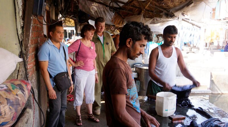 Hausdame Sabine, Provisionsmeister Miran und Laundry-Meister John auf dem Weg an Land. Es geht mehrere Kilometer durch die Innenstadt Mumbais zum Dhobi Ghat, dem größten Open-Air-Waschsalon auf der Welt. – Bild: BR/​Bewegte Zeiten GmbH/​Deborah Stöckle