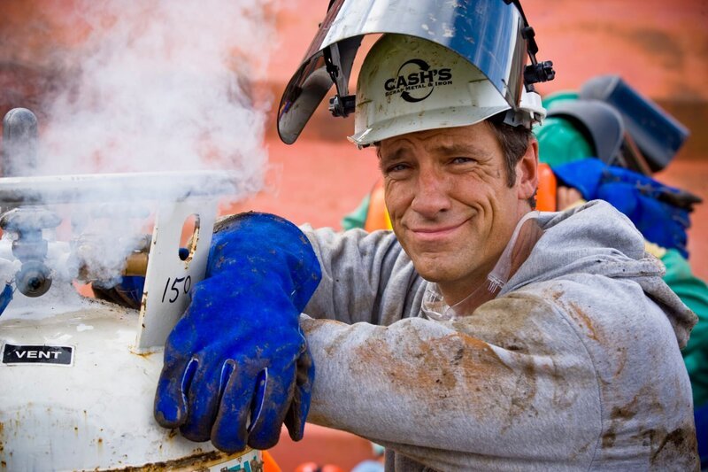 Cash’s Scrap Metal Portrait of Mike Rowe next to venting gas on torch bottles. Notice sticker „Pressure Building“ – Bild: Discovery Communications, Inc.