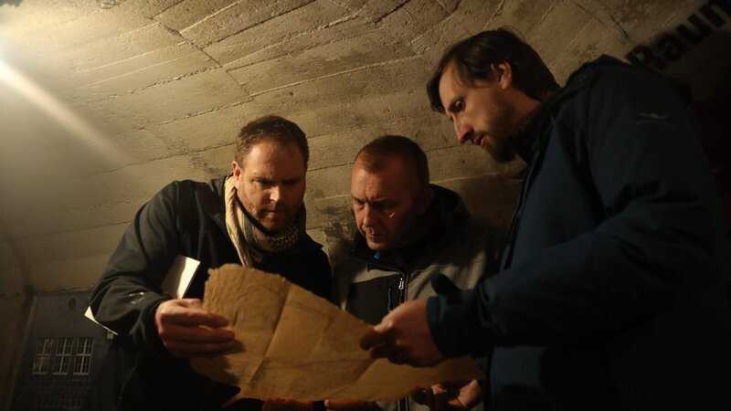 Sebastian Terenada und Oliver Kruger zeigen Josh Gates eine Karte des Nazitunnels. – Bild: Discovery Communications, LLC