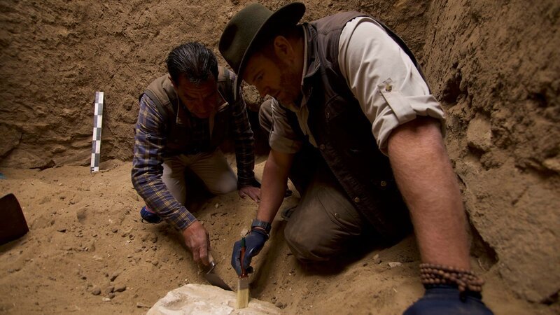 Josh Gates gräbt vorsichtig etwas aus, das ein Opfertisch zu sein scheint. – Bild: Warner Bros. Discovery