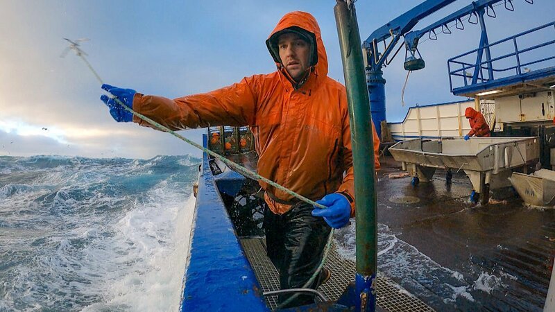 Northwestern deckhand Clark by the rail tossing hook – Bild: Warner Bros. Discovery, Inc.