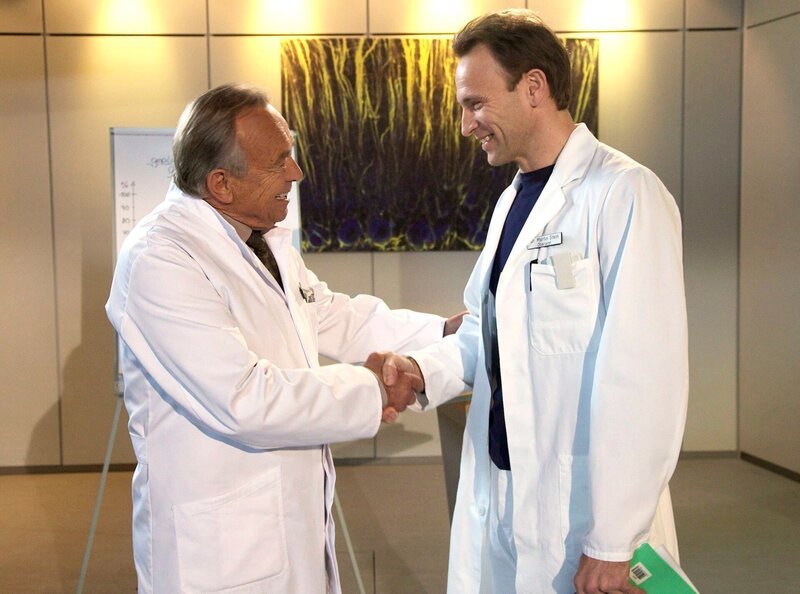 Prof. Simoni gratuliert Dr. Martin Stein. Er übernimmt interimsweise den Chefarztposten von Dr. Roland Heilmann, der sich mehr um seine an Brustkrebs erkrankte Frau kümmern möchte. – Bild: MDR/​MDR/​Saxonia/​Wernicke