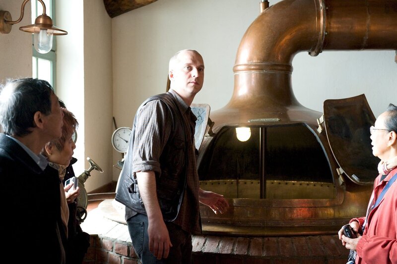 Weil sein Bruder Jörn nicht pünktlich kommt, führt Frank Holgersen (Matthias Matz) eine Gruppe Touristen durch dessen Traditionsbrauerei. – Bild: ZDF/​Marc Meyerbröker
