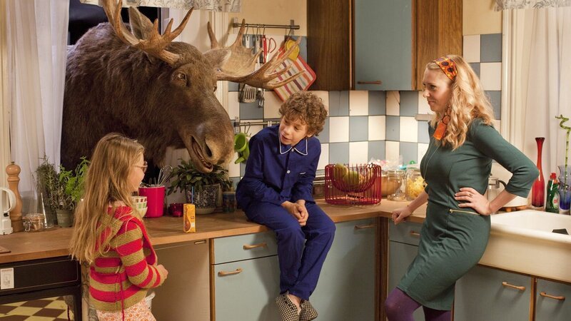 Der gestrandete Elch Moos (Brian Herring) steckt seinen Kopf durch das Küchenfenster, um mit Max (Dennis Reinsma), Kiki (Dana Goldberg) und ihrer Mutter Kirsten (Jelka van Houten) plaudern zu können. – Bild: KiKA/2013 Lemming Film BV, AB Svensk Filmindustri, Davaj Film, Filmpool Nord, Anchorage Entertainment/Victor Arnolds Der gestrandete Elch Moos (Brian Herring) steckt seinen Kopf durch das Küchenfenster, um mit Max (Dennis Reinsma), Kiki (Dana Goldberg) und ihrer Mutter Kirsten (Jelka van Houten) plaudern zu können. – Bild: KiKA/2013 Lemming Film BV, AB Svensk Filmindustri, Davaj Film, Filmpool Nord, Anchorage Entertainment/Victor Arnolds