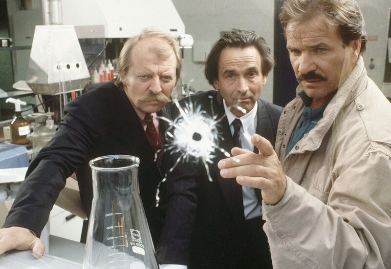 Horst Schimanski (Götz George, re.), sein Kollege Thanner (Eberhard Feik, li.) und Peter Schatz (Christoph Bantzer, Mitte) stossen im pharmazeutischen Labor auf Spuren des ermordeten Abteilungsleiter Jochen Bähr. – Bild: SWR/​WDR/​Bavaria