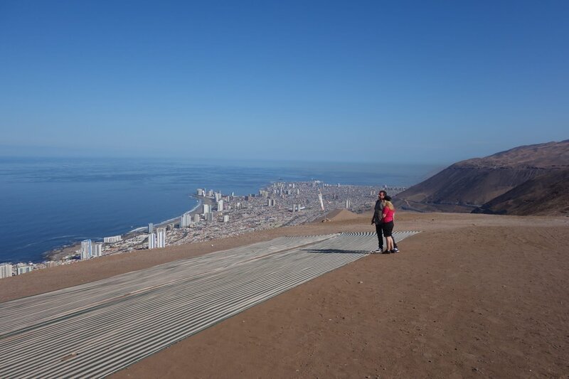 Iquique, Chile. Ausflug Paragliding: Petra und Frank Fautz wollen heute zusammen paragliden. In der Stadt treffen sie auf ihre Guides Christian, Maurizio. Zusammen fahren sie zur Stadt Alto Hospicio. Dort schauen sich Frank und Petra erstmal den Ausblick an. – Bild: Farah M’haimdat /​ BR, Bewegte Zeiten Filmproduktion GmbH /​ BR/​Bewegte Zeiten Filmproduktion GmbH/​Farah M’haimdat