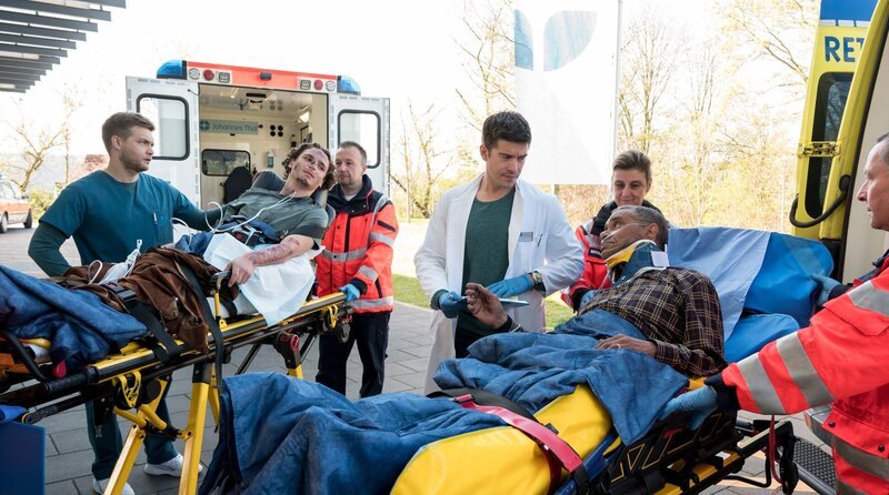 Arnulf Emmerling (Christofer von Beau, 2.v.r.) und Lukas Petersen (Jean-Luc Caputo, 2.v.l.) werden nach einem Hausbrand in die Notaufnahme des Johannes-Thal-Klinikum eingeliefert. Mikko Rantala (Luan Gummich, l.) und Ben Ahlbeck (Philipp Danne, M.) übernehmen die Patienten von den Rettungsanitäter:innen (Kompars:innen). – Bild: ARD/​Jens-Ulrich Koch
