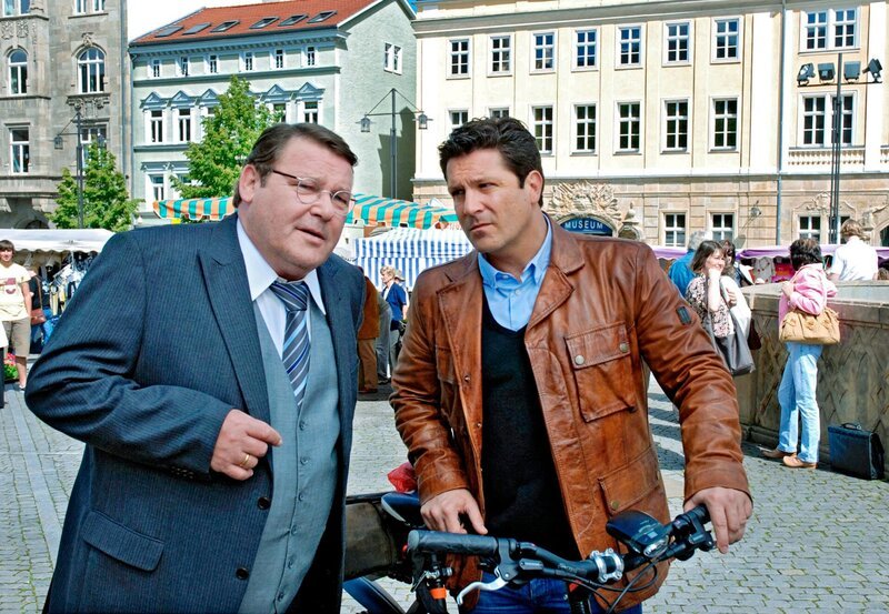 Dr. Kleist (Francis Fulton Smith, r.) und Bernd Sprengler (Walter Plathe, l.) unterhalten sich auf dem Marktplatz in Eisenach. – Bild: ARD/​Norbert Kuhröber