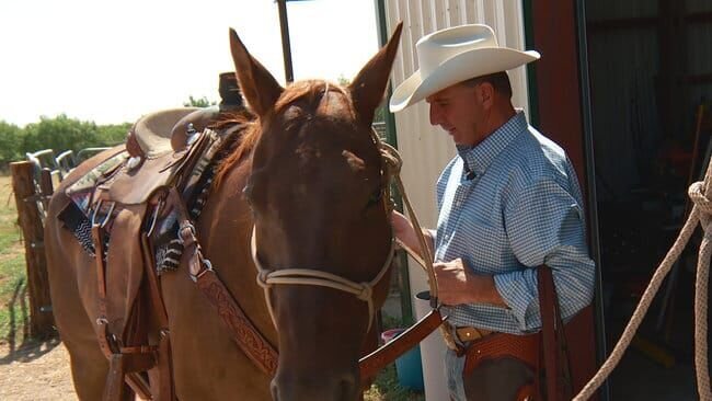 Warden Brown in plainclothes next to his brown horse, while wearing a cowboy hat – Bild: Animal Planet /​ Discovery Communications, LLC