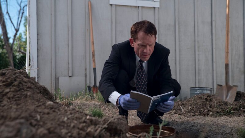 Detective squatting by dug out hole, reading a notebook that he found. – Bild: Greg Mazzola /​ Investigation Discovery /​ Discovery Communications, LLC