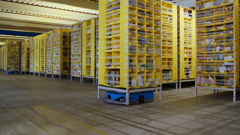 Blick in ein KI-unterstütztes Logistikzentrum von Amazon: Transportroboter bringen die Regale mit der benötigten Ware zu den Packern. – Bild: WeltN24 GmbH/​Like a Shot Entertainment Limited