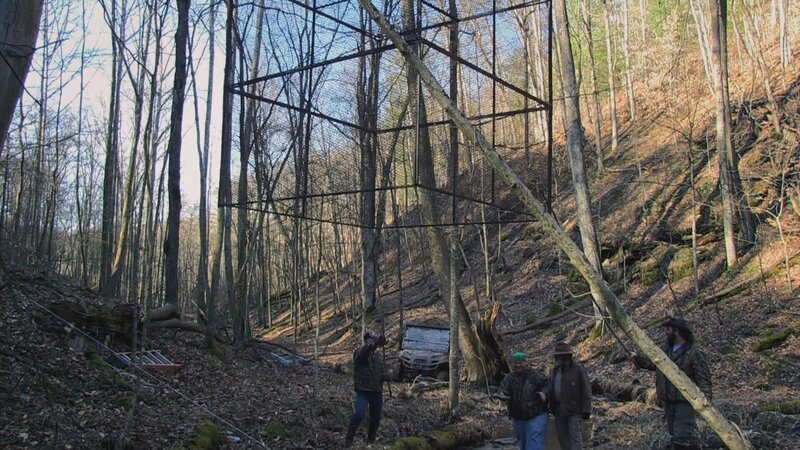 Jäger bereiten einen Käfig im Wald vor – Bild: Warner Bros. Discovery