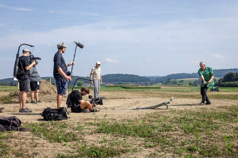 Wladimir Kaminer beim Hornussen. – Bild: SRF/​Severin Nowacki