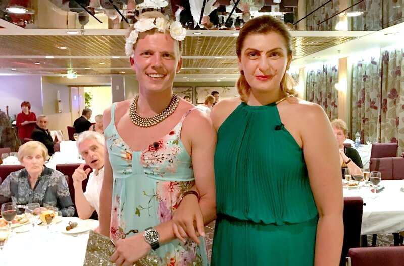 Reiseleiter Moritz hat ein Volleyballturnier verloren und muss nun Wettschulden einlösen. Moritz muss seine Wettschulden einlösen und besucht Anera zum Schminken und Umkleiden auf ihrer Kabine. Dort bekommt er sein Abend-Outfit gezeigt. Reiseleiter Moritz und seine Kollegin Anera beim Buffet Magnifique. – Bild: BR/​Gerrit Mannes