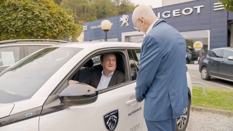Klaus Edelsbrunner – Autohändler und Bundesgremialobmann der Sparte Fahrzeughandel in der Wirtschaftskammer – empfängt Hanno Settele vor seinem Autohaus. Hanno Settele (l.) begutachtet gerade ein gebrauchtes E-Auto und fragt nach, wie E-Autos aktuell von potenziellen KonsumentInnen angenommen werden. – Bild: ORF/Neuland Film Klaus Edelsbrunner – Autohändler und Bundesgremialobmann der Sparte Fahrzeughandel in der Wirtschaftskammer – empfängt Hanno Settele vor seinem Autohaus. Hanno Settele (l.) begutachtet gerade ein gebrauchtes E-Auto und fragt nach, wie E-Autos aktuell von potenziellen KonsumentInnen angenommen werden. – Bild: ORF/Neuland Film
