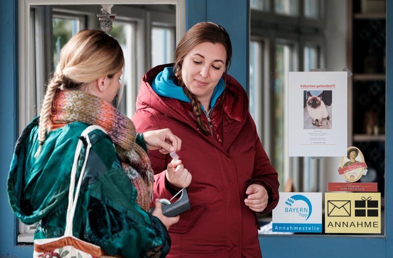 Sarah (Sophie Reiml, links) reicht Sophia (Patricia Freund, rechts) einen Klebestreifen, um die Suchplakate für das Kätzchen aufzuhängen. – Bild: BR/​Lena Semmelroggen