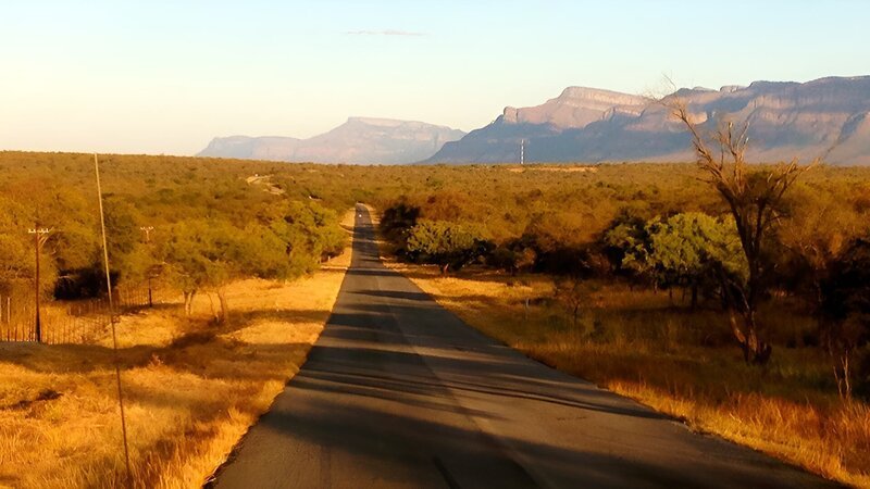 A road in the center of the desert leading to the mountains. – Bild: Discovery Communications