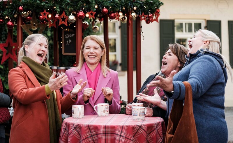 Vera, Uschi, Rosi und Ulla trällern fröhlich Veras Ohrwurm auf dem Weihnachtsmarkt. Von links: Vera (Sybille Waury), Uschi (Silke Popp), Rosi (Brigitte Walbrun), Ulla (Sabrina Dietel). – Bild: Lena Semmelroggen /​ BR